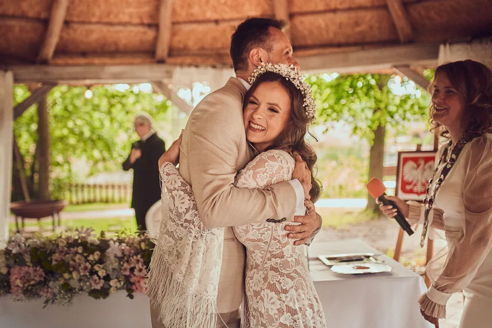 Roześmiana panna młoda w uścisku pana młodego