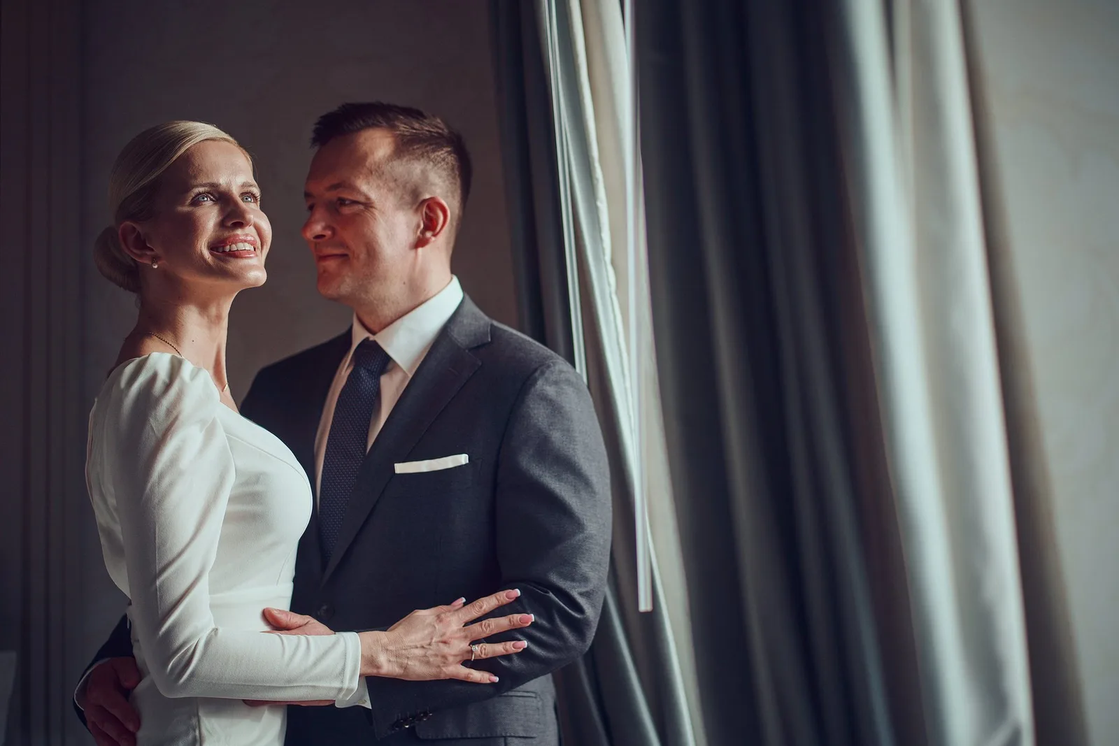 Para młoda przy oknie z zasłonami