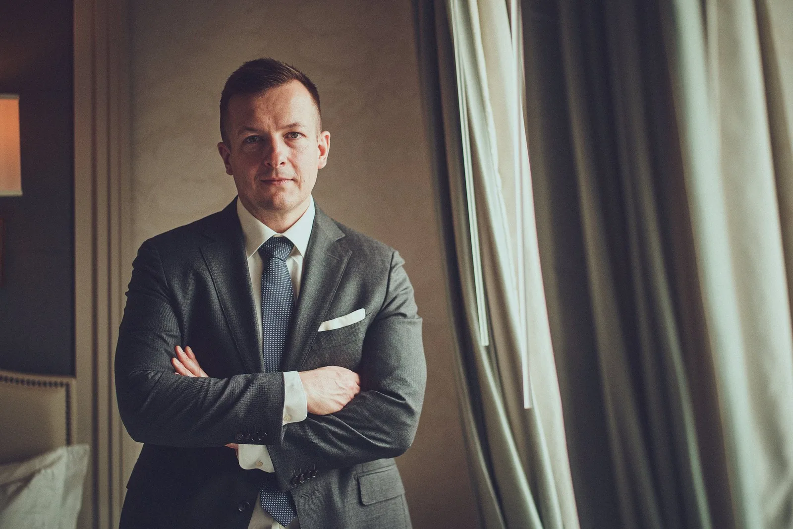 Pan młody ze skrzyżowanymi rękami przy oknie
