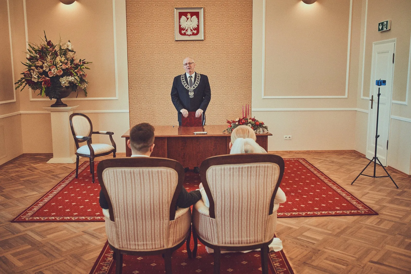 Sala ślubów z godłem, para młoda przed urzędnikiem