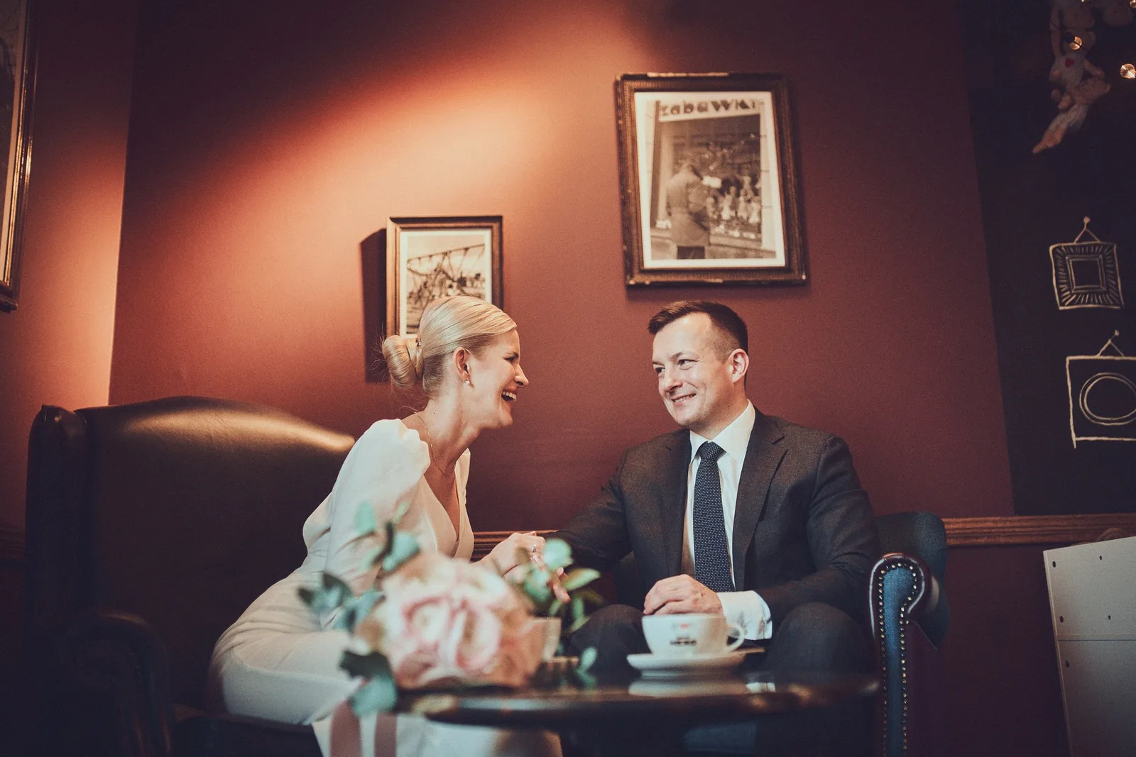 Para młoda przy stoliku pod czerwoną ścianą